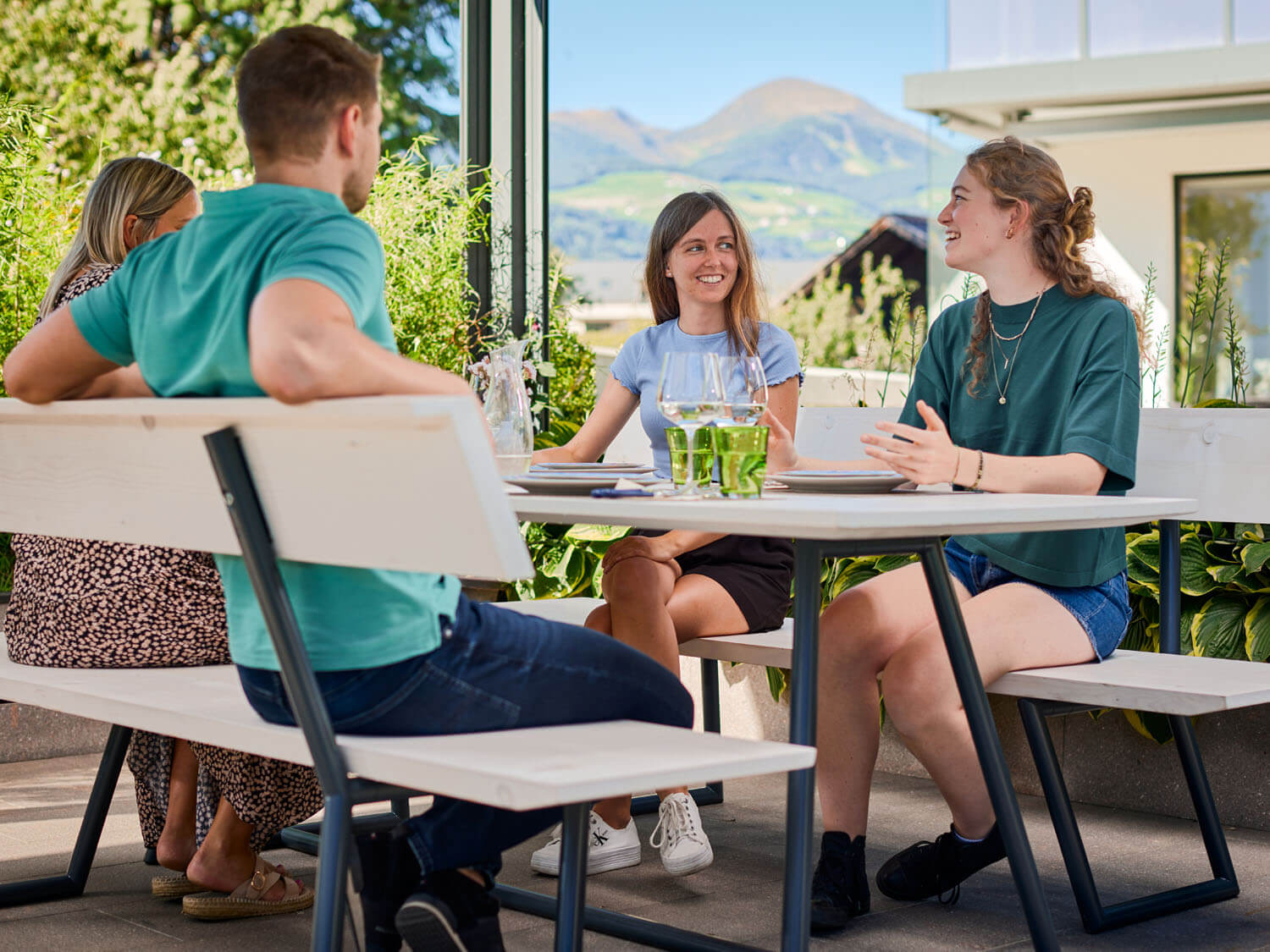 Vier Personen sitzen im Garten auf der Designgarnitur Riva und unterhalten sich.