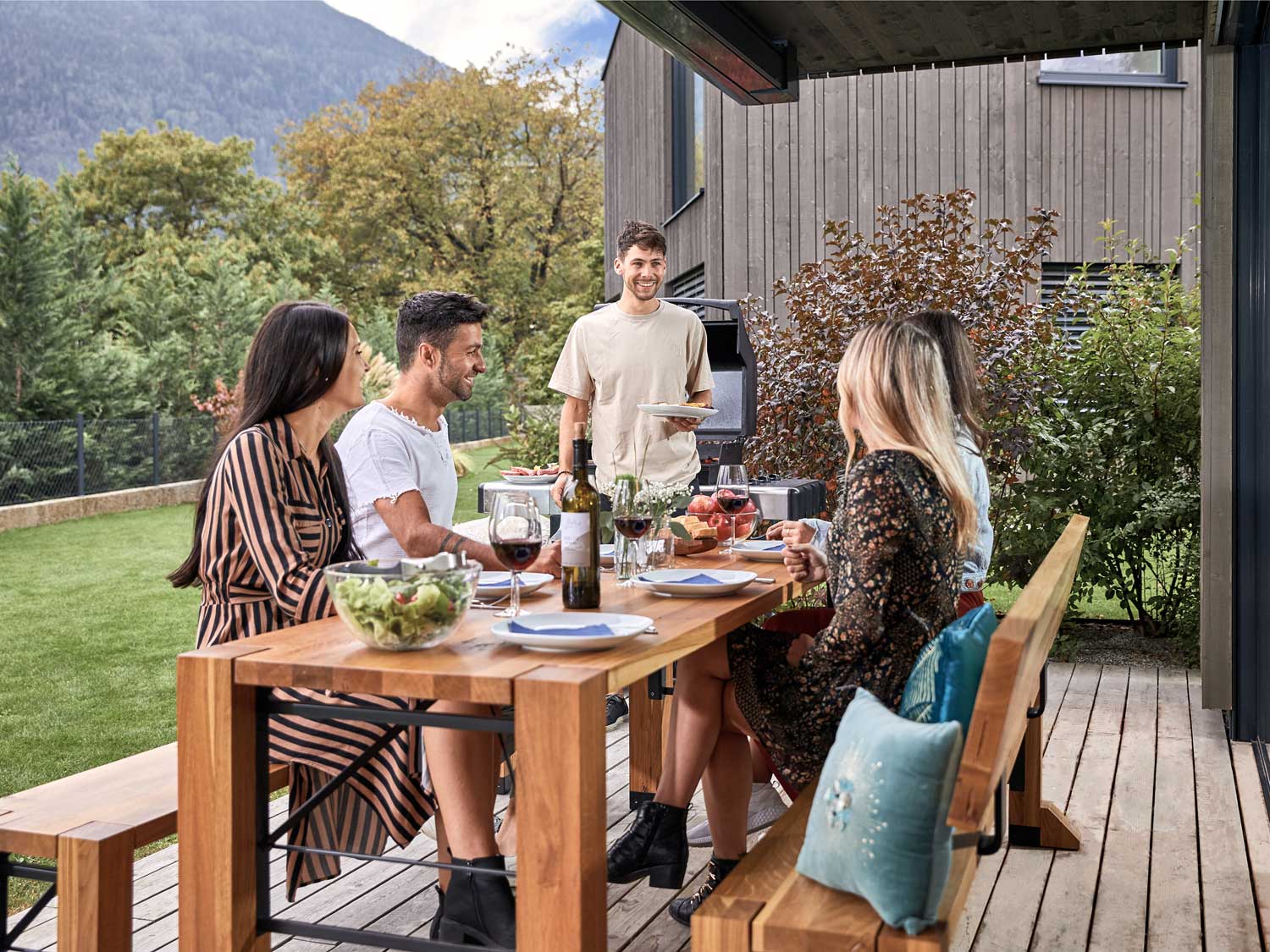 Auf der Terrasse essen fünf Personen auf der gedeckten Designgarnitur Lago.