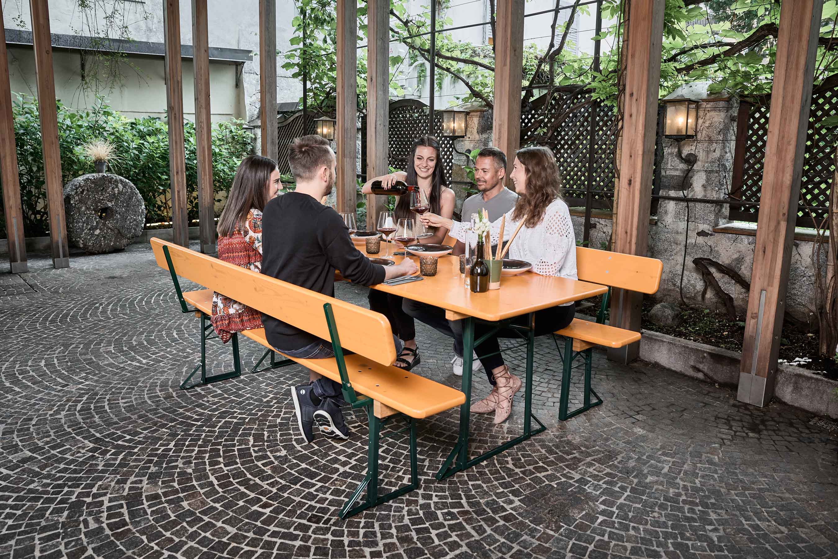 Cinque persone pranzano nell'area esterna di un pub e si siedono su set da birreria classico.