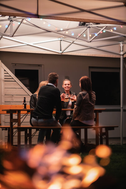 A convivial group of four people are sitting on a Rustica furniture set in the garden.