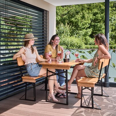 Kleine Bierzeltgarnitur Shorty mit Lehne auf der Terrasse Freunde sitzen gemeinsam auf der kleinen Bierzeltgarnitur Shorty mit Lehne.