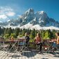 Biergartenmmöbel auf der Terrasse in den Bergen Mehrere Personen sitzen auf einer Terrasse auf den Biergartenmöbel mit Blick auf die Berge.