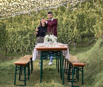 Ein Paar geht zu einer geschmückten Biergartentischgarnitur.