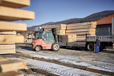 The image shows a forklift loading wooden slats for beer tent sets onto a truck.