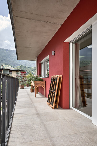 Auf einem Balkon ist die kleine Bierzeltgarnitur Shorty zusammengeklappt und an die Wand gestellt.