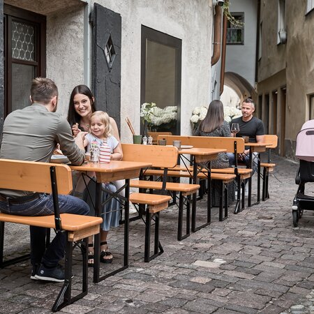Small beer garden table set Shorty with backrest in alleyway Several people sitting on small beer garden table sets in an alley near a restaurant.