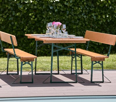 Wide beer garden table set with backrest in pine Wide beer garden table set with backrest in pine stands covered on the terrace.