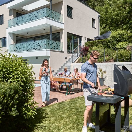 A barbecue party is taking place and the wide beer garden table set with backrest is used to relax.