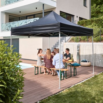 Under a canopy tent, five people are on a classic beer garden table sets.
