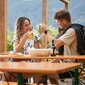 Klassische Bierzeltgarnituren beim Guggerhof Ein Paar stoßt mit zwei Bierkrügen zusammen und sitzt dabei auf klassische Bierzeltgarnituren.