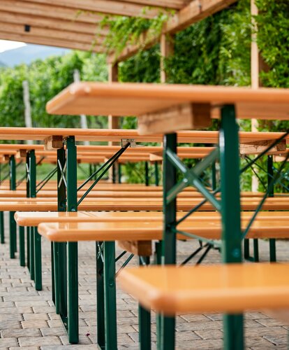Row of classic beer tent sets with green metal frames and natural wood.