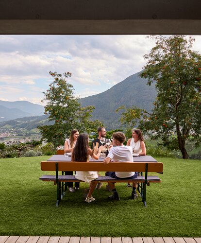 Breite Bierzeltgarnitur in geselliger Atmosphäre An dem gedeckten Biergartentisch sitzen mehrere Personen und verbringen einen geselligen Abend.