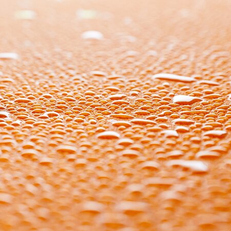 There are many drops of water on the surface of the beer garden table set.