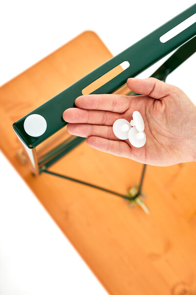Bodenschoner an einem Untergestell. Eine Hand hält drei weitere Bodenschoner.
