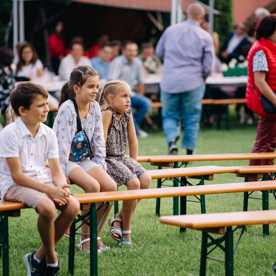Kinder sitzen auf Bierbänken Kinder unterschiedlichen Alters sitzen auf RUKU1952 Bierbänken und blicken in die Ferne.