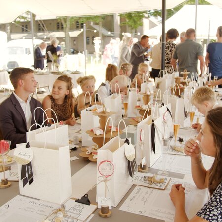 Many children sit at a table on a beer table set at a wedding.