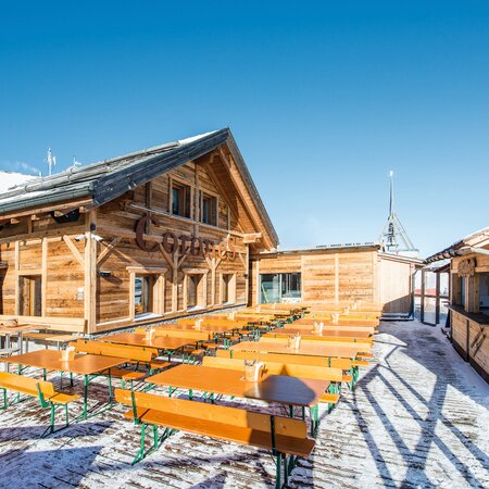 There are many wide beer garden table sets on a cottage in winter.