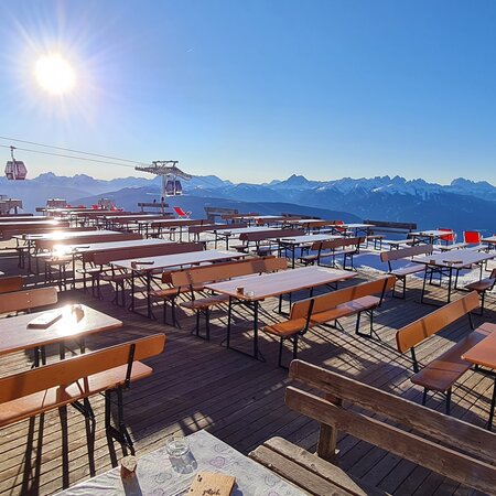 Wide beer garden table sets with backrest are placed in front of a hut in winter.