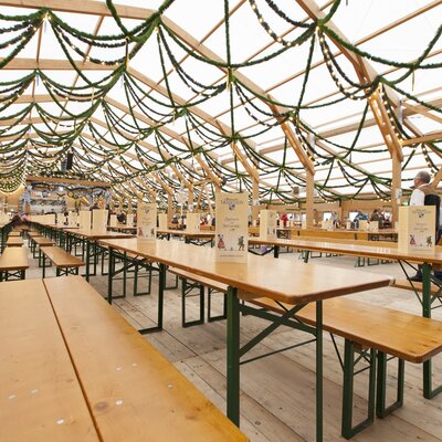 L’immagine mostra l’interno di una tenda dell’Oktoberfest, con file di set da birreria Classic.