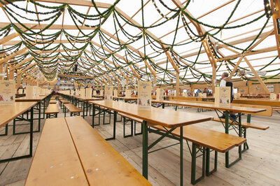 L’immagine mostra l’interno di una tenda dell’Oktoberfest, con file di set da birreria Classic.