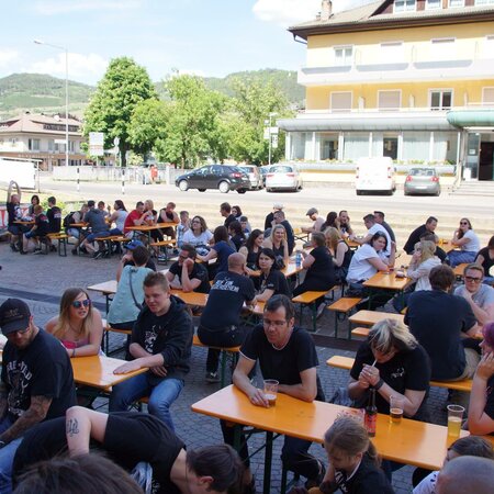  At the Rookies & Kings event, many people sit outside on beer table sets and chat.
